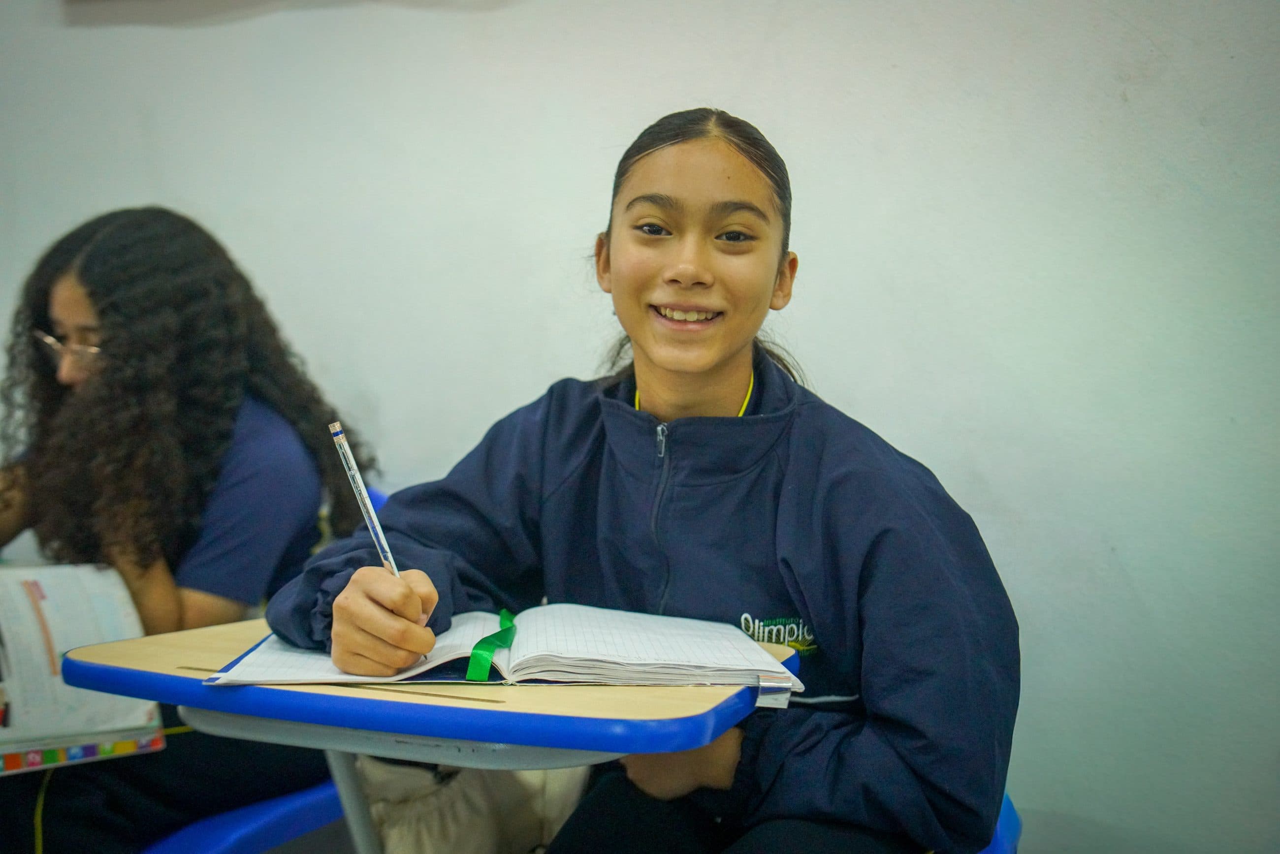 Alumna escribiendo en su cuaderno en un salón del Instituto Olimpia