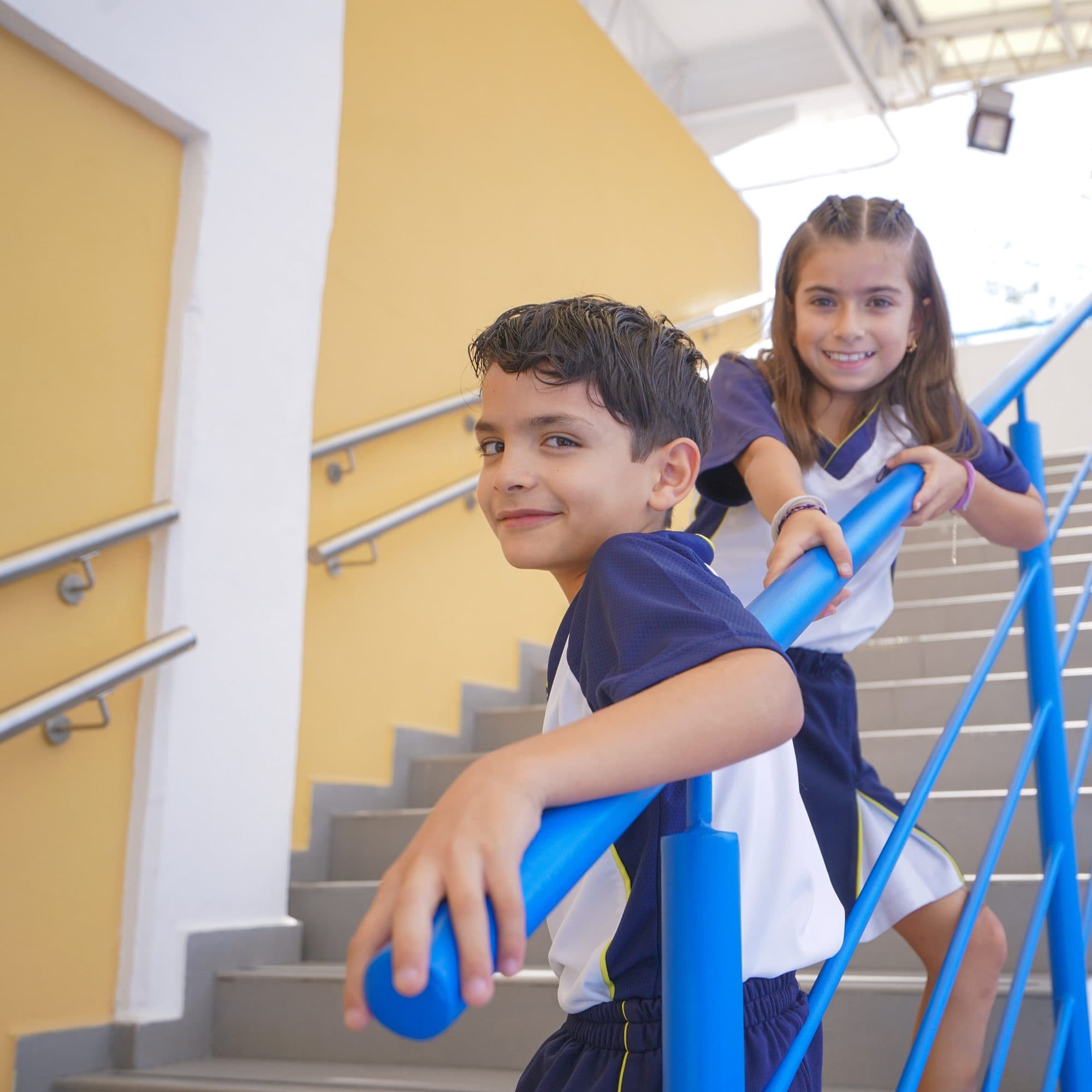Alumno y alumna del Instituto Olimpia en el barandal de la escalera